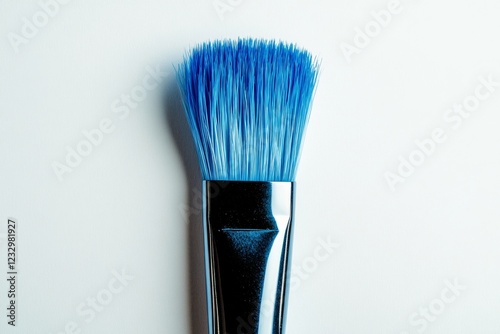 Artistic blue paint brush resting against a light background showcasing vibra...