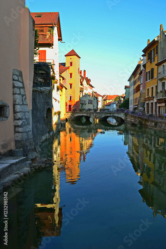 Annecy is an old city in eastern France. Reflections of colored houses in the river and flowers along the embankment.