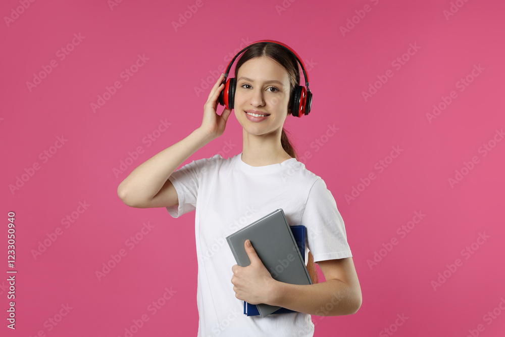 Portrait of smiling teenage girl in headphones with books on pink background Portrait of smiling teenage girl in headphones with books on pink background