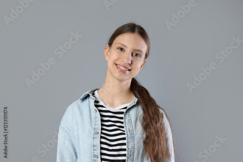 Portrait of smiling teenage girl on grey background
