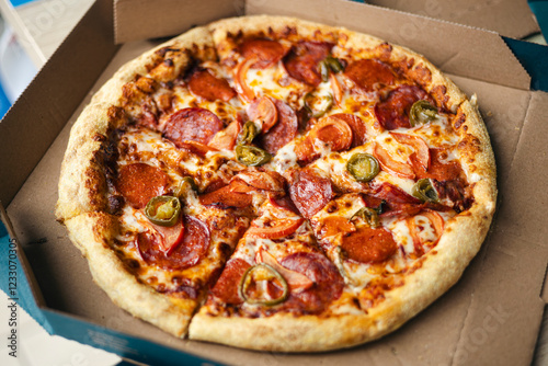 Fresh pepperoni pizza in a cardboard box on a table photo