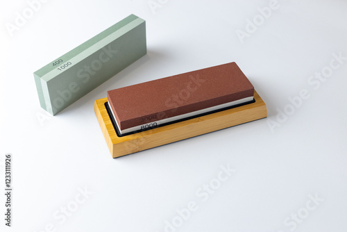 white background on table lies all the equipment a set for sharpening and polishing kitchen knives and various blades different abrasiveness of stones a retainer for knives