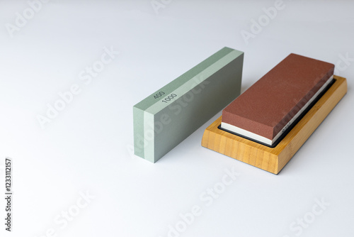 closeup white background on table lies all the equipment a set for sharpening and polishing kitchen knives and various blades different abrasiveness of stones a retainer for knives