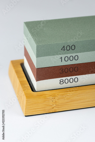 closeup white background on table lies red and green equipment a set for sharpening and polishing kitchen knives and various blades different abrasiveness of stones a retainer for knives