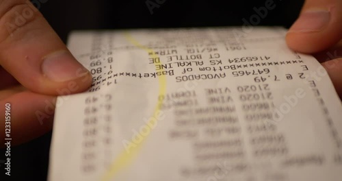 Close-up Receipt Person Hands of Shopper Reading Accounting Report After Buying or Purchase Credit. Till Slip Woman Holding Finance Document After Buying or Shopping in Supermarket. Slow motion.