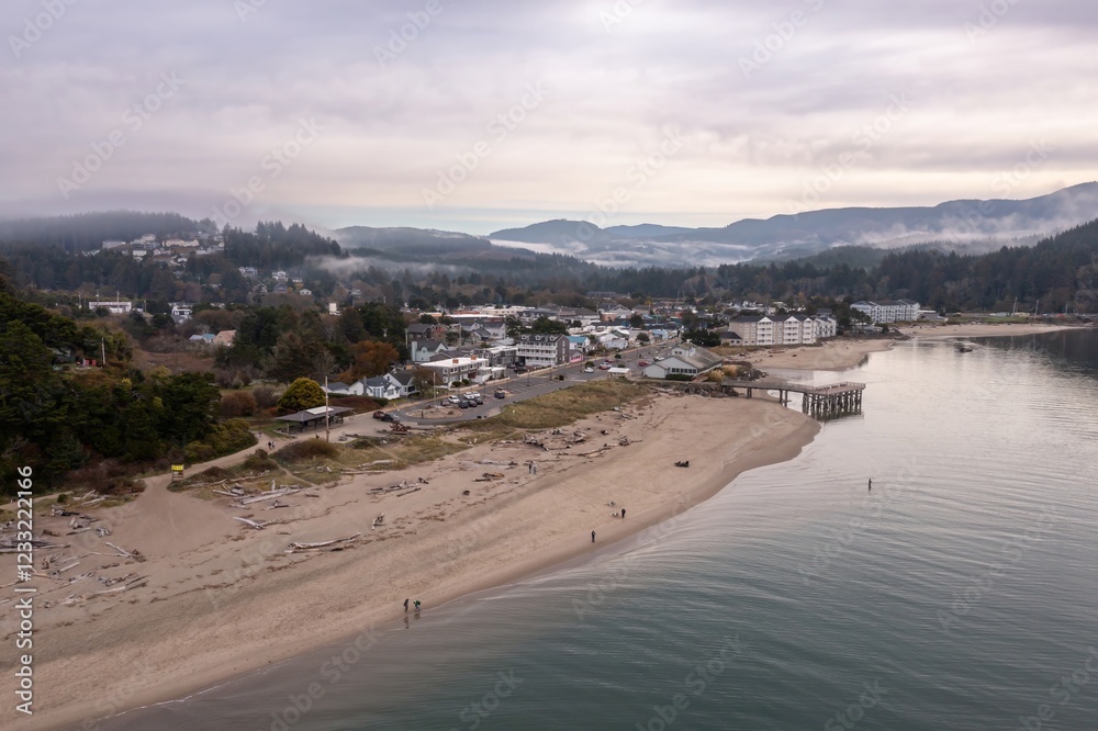 Lincoln City shrouded in fog, with people walking along the Siletz Bay beach. Misty mountains in the background. Oregon, USA Lincoln City shrouded in fog, with people walking along the Siletz Bay beach. Misty mountains in the background. Oregon, USA