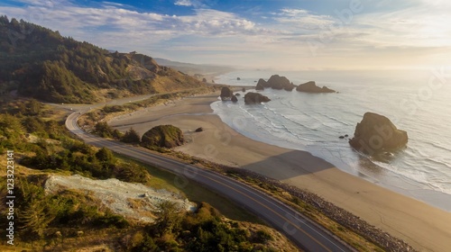 Coastal highway winds along a scenic beach at sunset. Highway 1 curves along the Pacific Ocean, showcasing dramatic rock formations. Golden light bathes the landscape.  Pistol River Beach, Oregon, USA