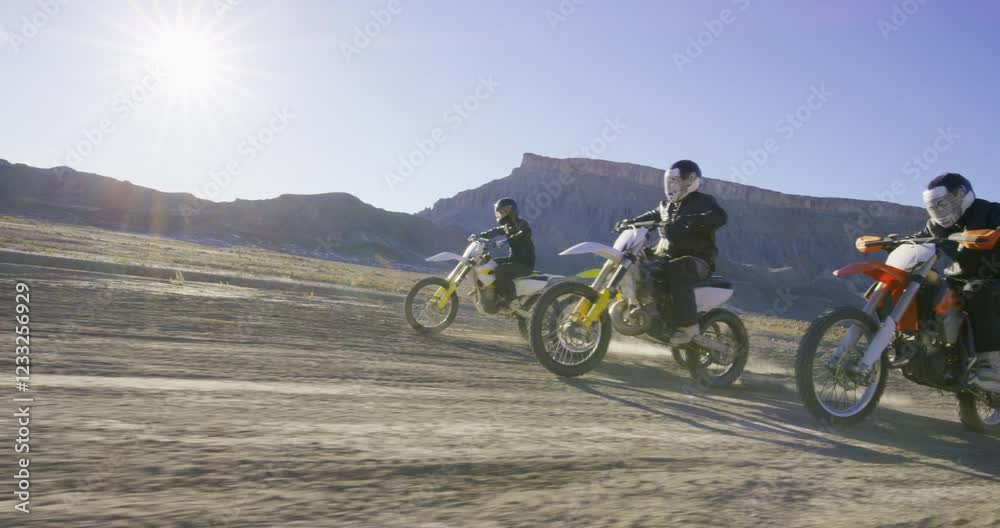 Low shot following motorcyclists and van through beautiful desert with sun flare Low shot following motorcyclists and van through beautiful desert with sun flare