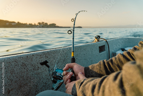 Obraz na płótnie Hands Holding a Fishing Rod from a Boat as the Sun Rises Over the Sea w salonie