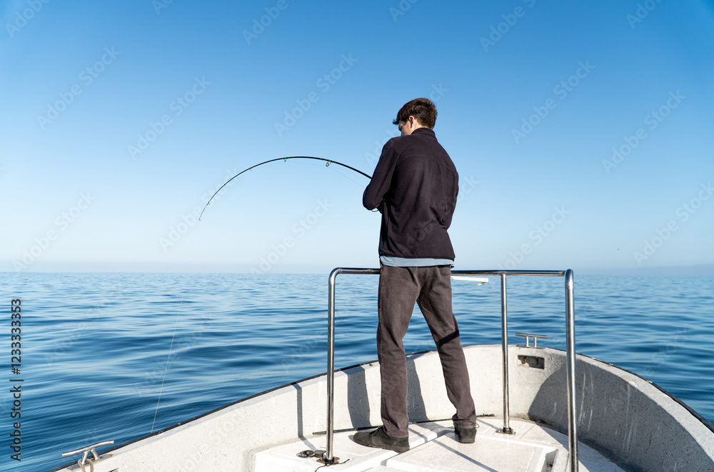 View from Behind of a Young Boy Fishing from a Boat in the Sea