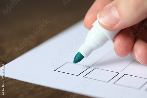 Woman checking box of paper form at wooden table, closeup