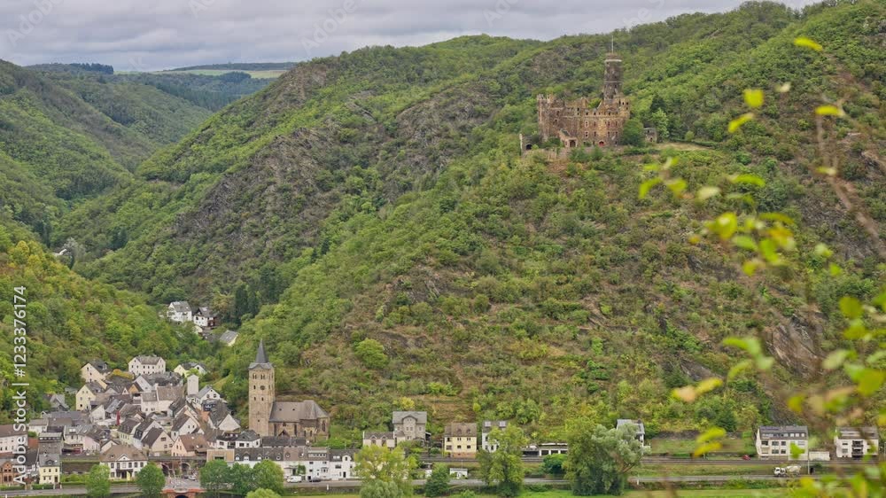 Rural village near the Rhine River with steep towering hills including a medieval castle on the hilltop, Rhine Valley, Germany Rural village near the Rhine River with steep towering hills including a medieval castle on the hilltop, Rhine Valley, Germany