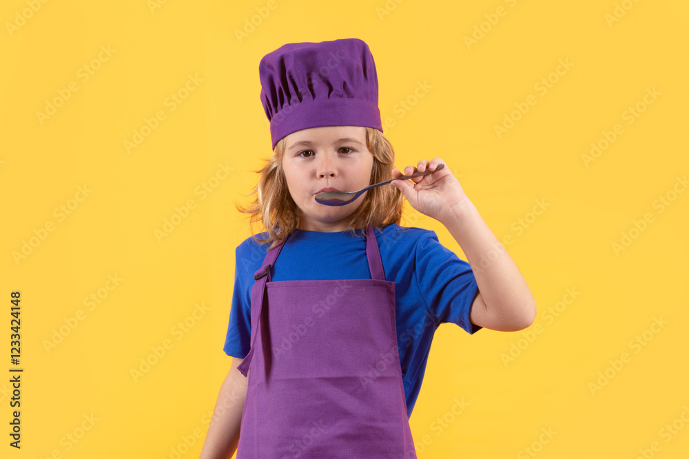 Funny kid chef cook with spoon, studio portrait. Child cooking, little chef prepares food. Kid boy in chefs hat and apron on yellow studio isolated background. Funny kid chef cook with spoon, studio portrait. Child cooking, little chef prepares food. Kid boy in chefs hat and apron on yellow studio isolated background.