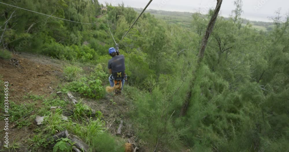 Man and his dog riding zip line together over beautiful jungle in epic slow motion