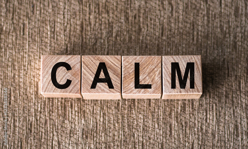 Fototapeta premium Scrabbled wooden blocks arranged to spell the word calm on a surface.