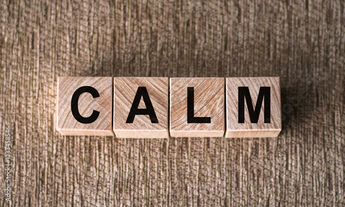 Scrabbled wooden blocks arranged to spell the word calm on a surface.