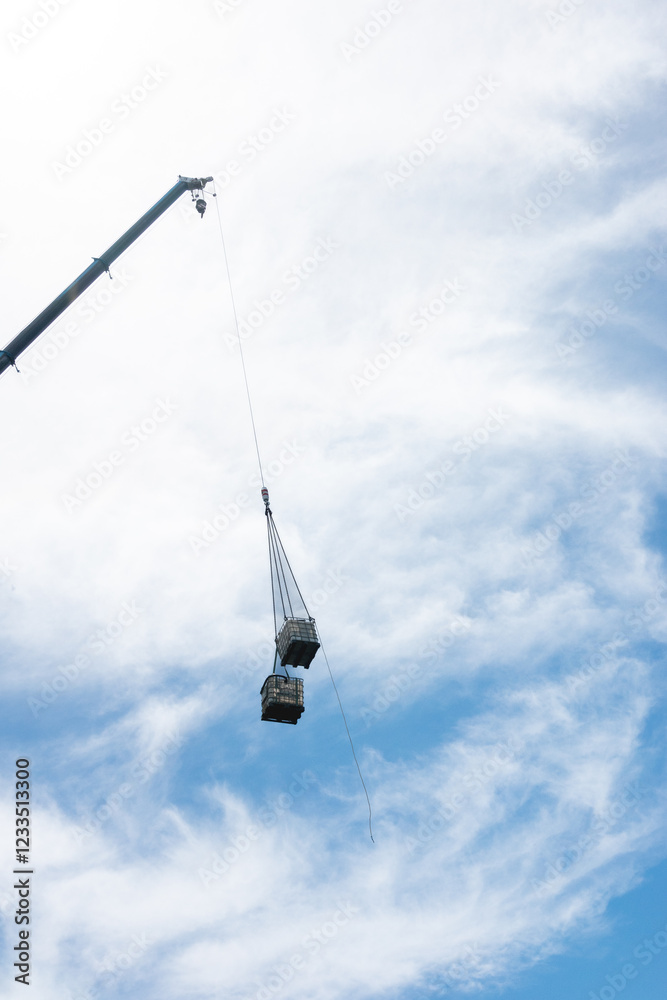 Low point of view of crane lifting load high into sky Low point of view of crane lifting load high into sky