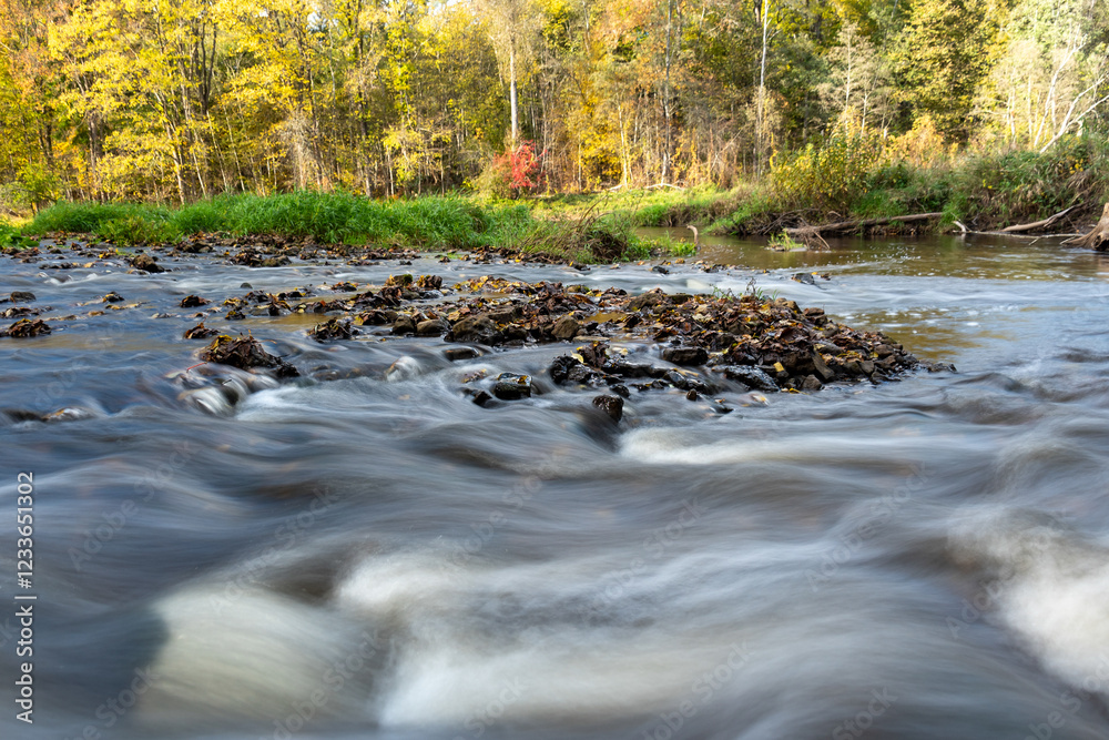 fast river between stones, stream of water passes the stone, ecology in the river, beautiful natural environment as background, blurred stream of water fast river between stones, stream of water passes the stone, ecology in the river, beautiful natural environment as background, blurred stream of water