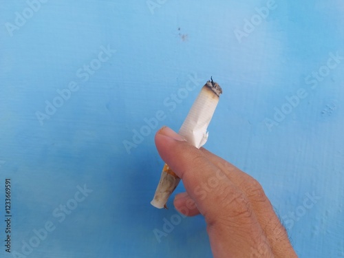 a cigarette gripped with 2 fingers