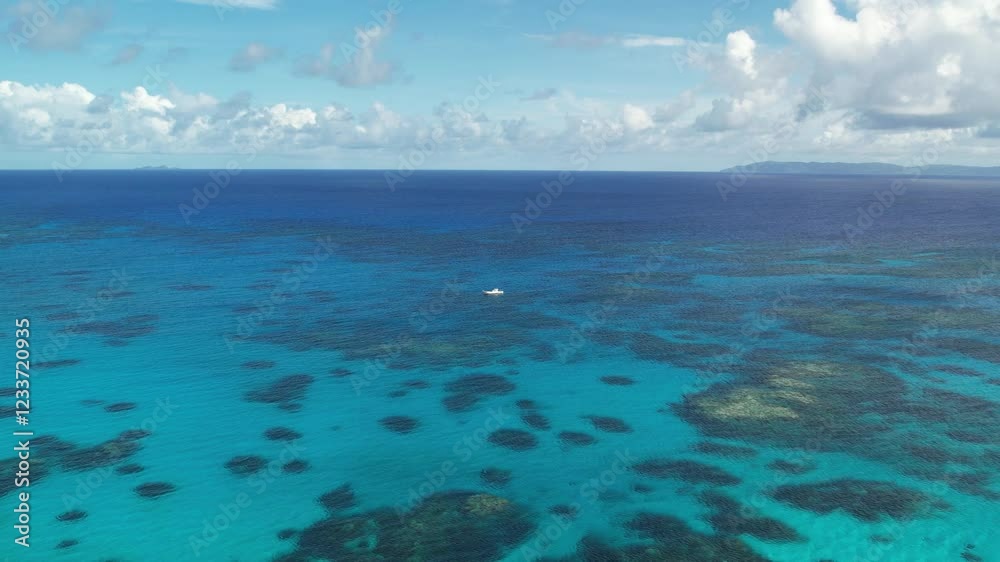 Aerial drone shot of a boat floating on crystal-clear shallow waters, revealing vibrant coral reefs below. Perfect for travel, marine, and tropical paradise visuals. Aerial drone shot of a boat floating on crystal-clear shallow waters, revealing vibrant coral reefs below. Perfect for travel, marine, and tropical paradise visuals.