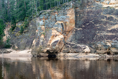 landscape with sandstone cliffs on the river bank, sandy river bank, old last year's grass, nature without greenery, Erglu cliffs, Cesu county, Latvia photo