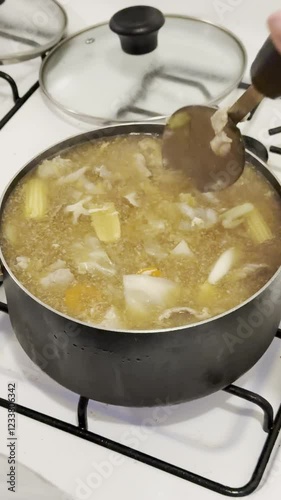 Making and scooping soup in the pot on the stove: Mixed vegetables and pork for Thai soup.