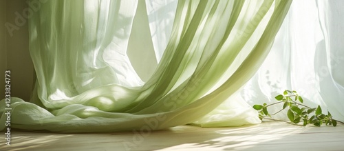 Soft green sheer curtains gently flowing in natural light with wooden floor and a plant for interior design concept Copy Space photo