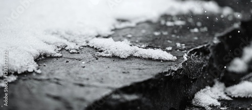 Panel kuchenny z motywem Close-up of snow-covered slate rock surface with snowflakes and blurred background, black and white image with Copy Space.