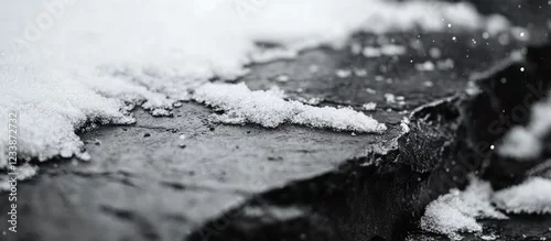 Obraz  z motywem Close-up of snow-covered slate rock surface with snowflakes and blurred background, black and white image with Copy Space.