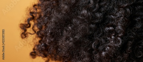 Close-up of textured curly hair against an orange background with Copy Space for text placement