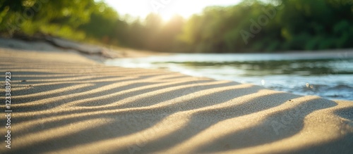 Fototapeta Naklejka Na Ścianę i Meble -  Rippling sand patterns at riverbank during sunset with lush green backdrop and gentle water flow in natural lighting Copy Space