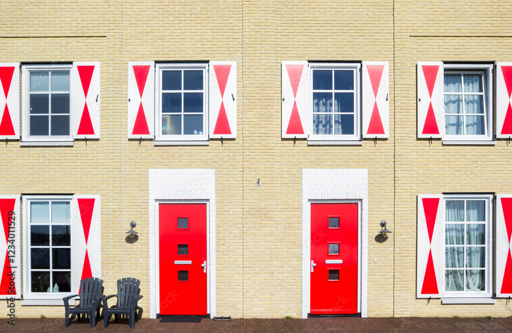 Front facade of a house with red doors and shutters in Blauwestad, Netherlands