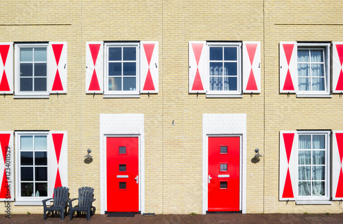 Obraz na płótnie Front facade of a house with red doors and shutters in Blauwestad, Netherlands w salonie