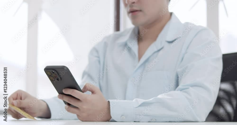 A male individual is doing an online transaction using his mobile phone and credit card. A male individual is doing an online transaction using his mobile phone and credit card.