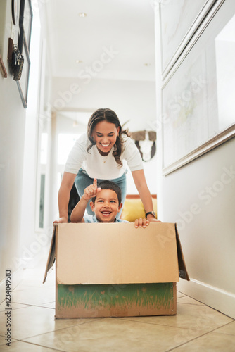 Box, moving house and mother pushing son for having fun or playing game in new home together. Cardboard, pointing and smile of woman parent with boy child in apartment for property investment