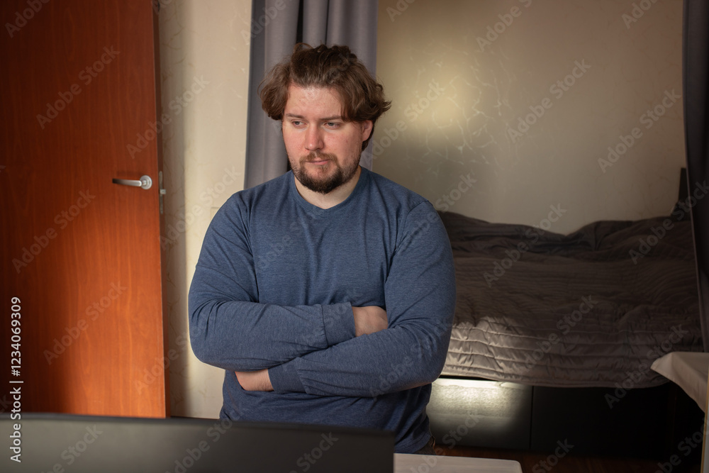 Sad man working on laptop, reacting to a stressful situation at a table, focusing on a freelance task in a casual environment. Sad man working on laptop, reacting to a stressful situation at a table, focusing on a freelance task in a casual environment.