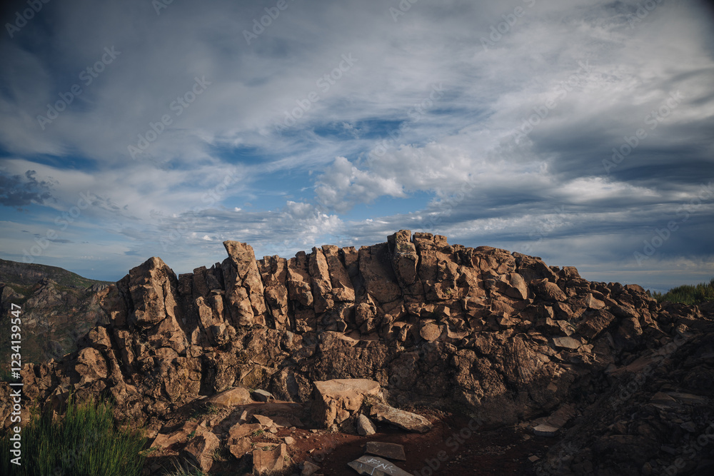 Obraz premium A rugged rock formation stands prominently amidst a breathtaking landscape, with clouds rolling in the sky above. The rocky surface reflects the natural beauty of the area.