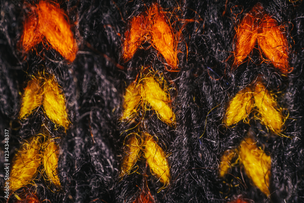 A macro view of black knitted fabric featuring vibrant orange and yellow patterns. The intricate stitching and bold color contrast create a striking design. A macro view of black knitted fabric featuring vibrant orange and yellow patterns. The intricate stitching and bold color contrast create a striking design.