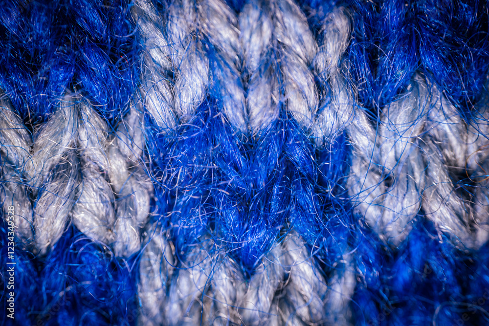 Obraz premium A macro view of blue knitted fabric with a repeating white pattern, highlighting the intricate stitching and soft texture. The design creates a cozy and artistic feel.