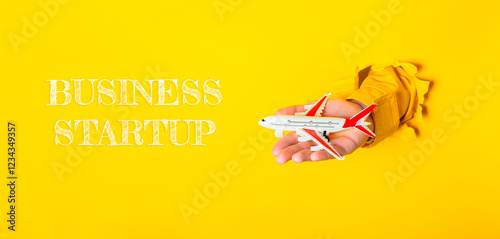 Hand holding a toy airplane with the words Business Startup written below it photo