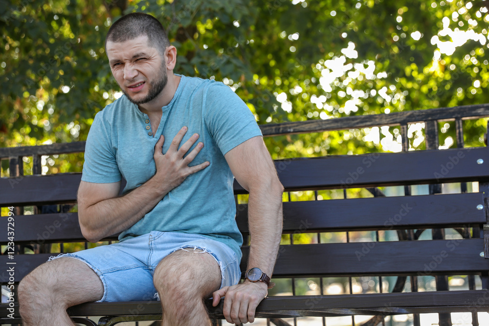 Man with heart attack sitting on bench in park Man with heart attack sitting on bench in park