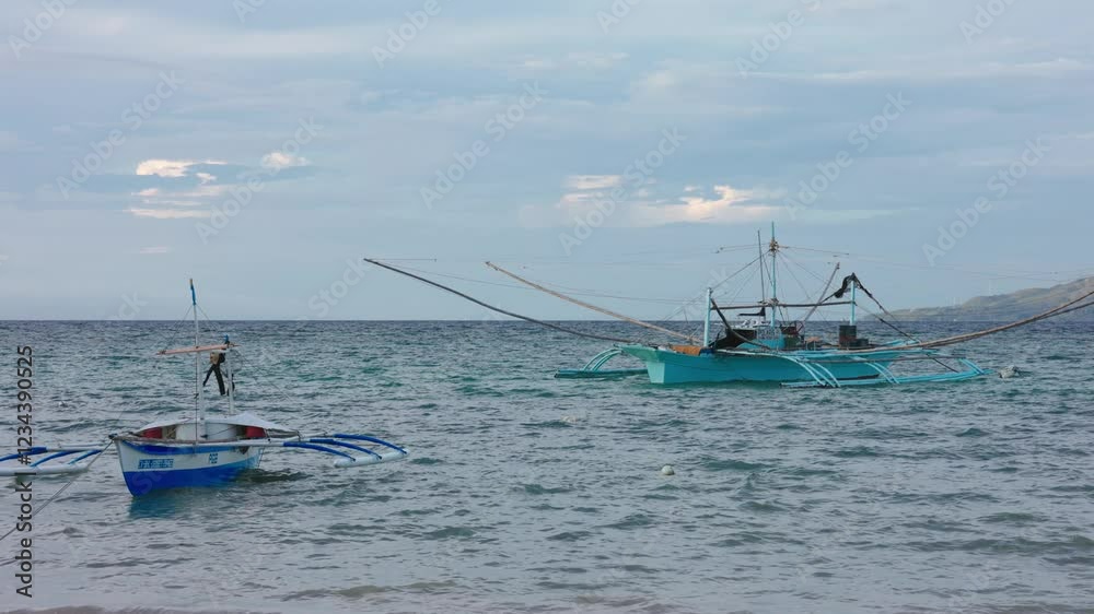 One big, one small traditional bangka boat in the sea at the Philippines One big, one small traditional bangka boat in the sea at the Philippines
