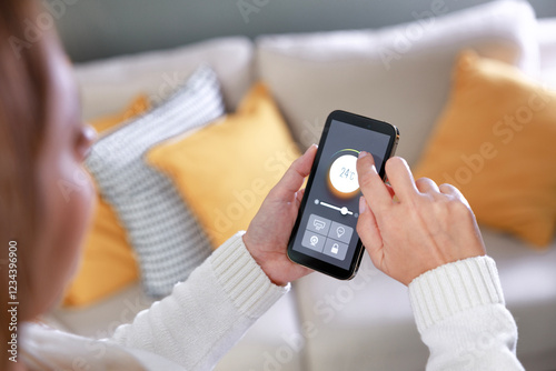 Woman adjusting the temperature of her house using a mobile app on her smart phone