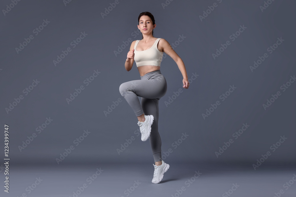 Obraz premium Woman in sportswear exercising on grey background