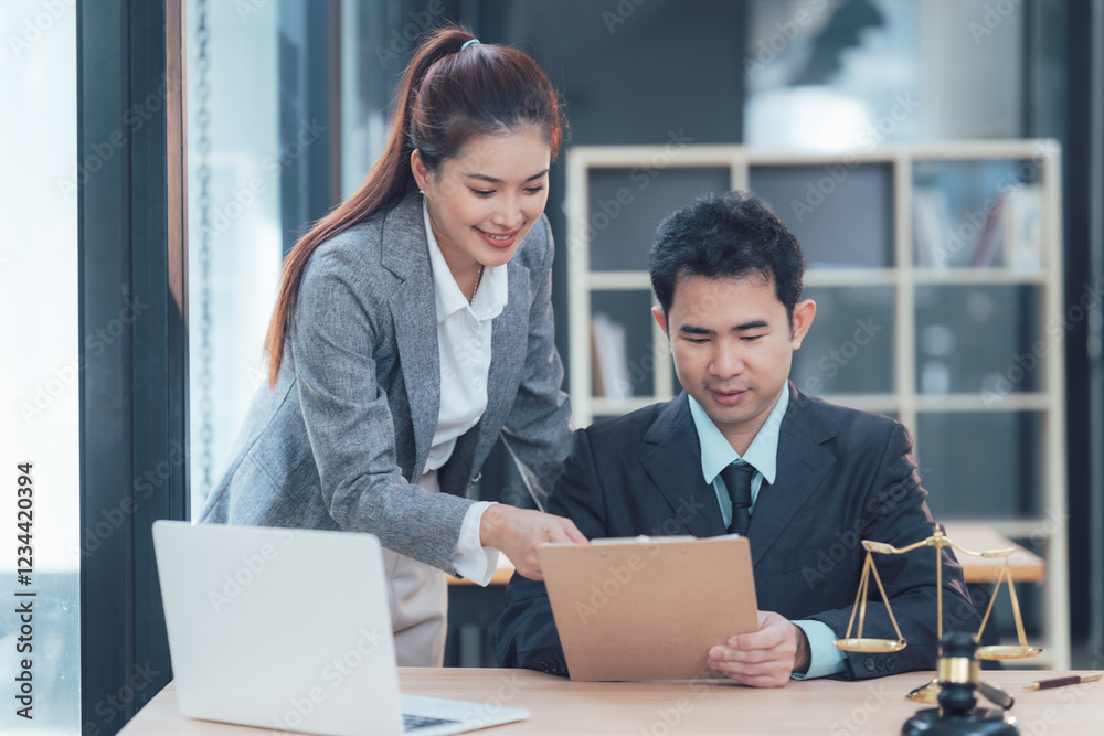 Collaborative Legal Expertise: Two professionals, a man and a woman in formal attire, engage in a focused discussion over legal documents.