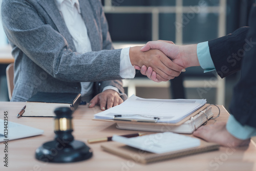 Legal Partnership: A close-up shot of two businesspeople shaking hands across a table, symbolizing a successful legal partnership.  A judge's gavel rests subtly in the foreground.