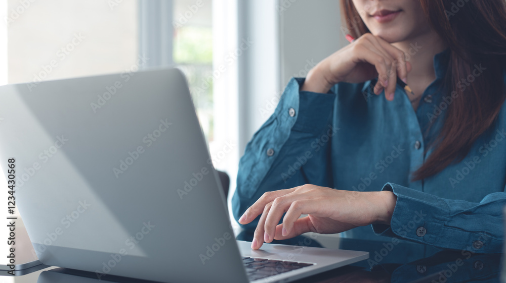 Fototapeta premium Business woman working on laptop computer at modern office. Pensive business woman thinking of problem solution, using laptop, planning and surfing the internet searching some ideas