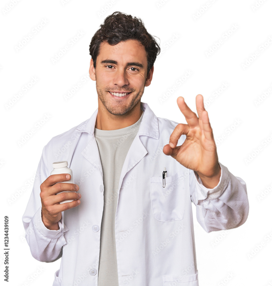 Young Hispanic pharmacist with pills cheerful and confident showing ok gesture. Young Hispanic pharmacist with pills cheerful and confident showing ok gesture.