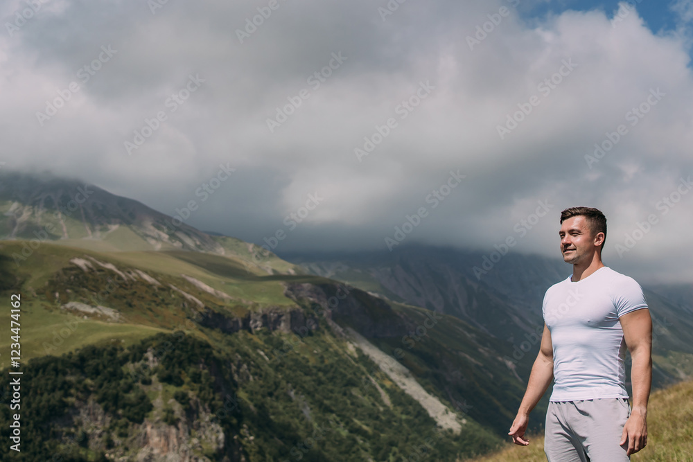 Naklejka premium Young men is enjoying the mountain view. Summer landscape on the Georgian Military Road. Green slopes, deep gorge, and cloudy sky. Freedom and nature concept