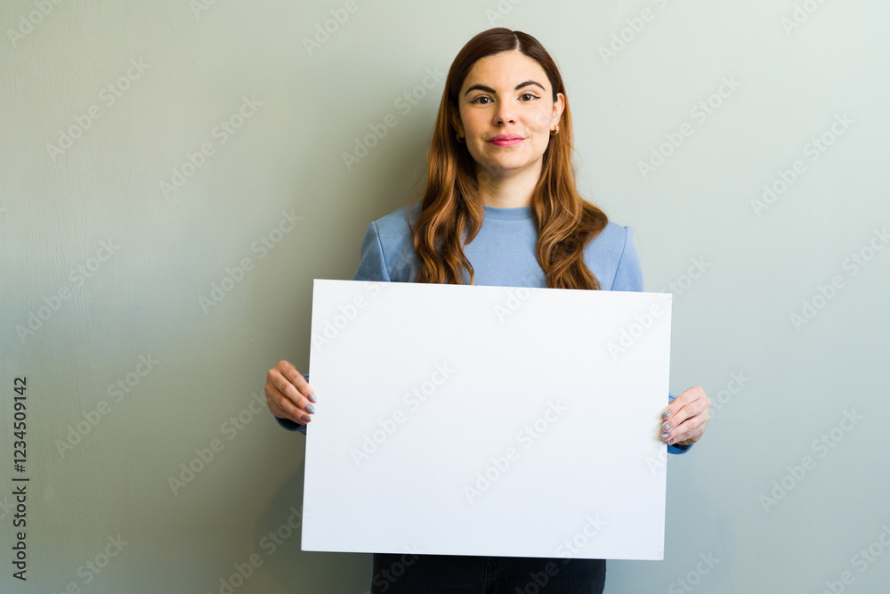 Young woman holding blank white sign against gray wall Young woman holding blank white sign against gray wall